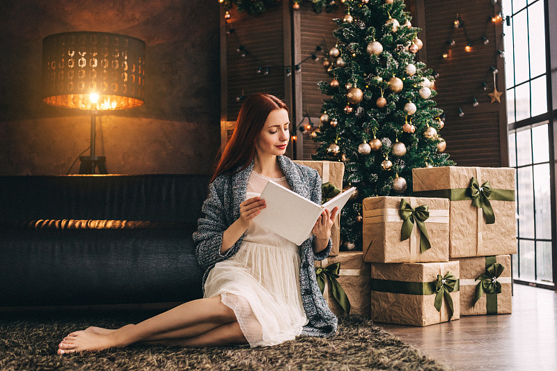 女人坐在地板附近的新年冷杉图片下载