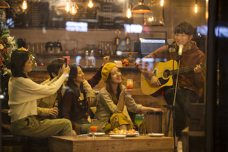 五个青年男女在酒吧弹吉他唱歌喝酒一起欢度圣诞节平安夜图片下载