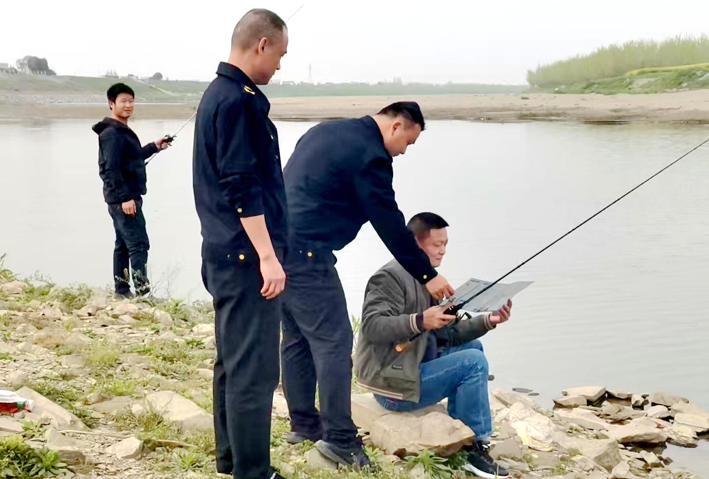 图为执法人员对沿岸钓鱼群众进行劝导教育。吴芷英摄