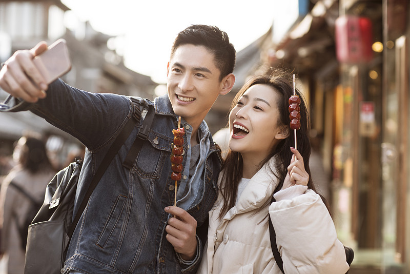 快乐的情侣在胡同用手机自拍图片下载