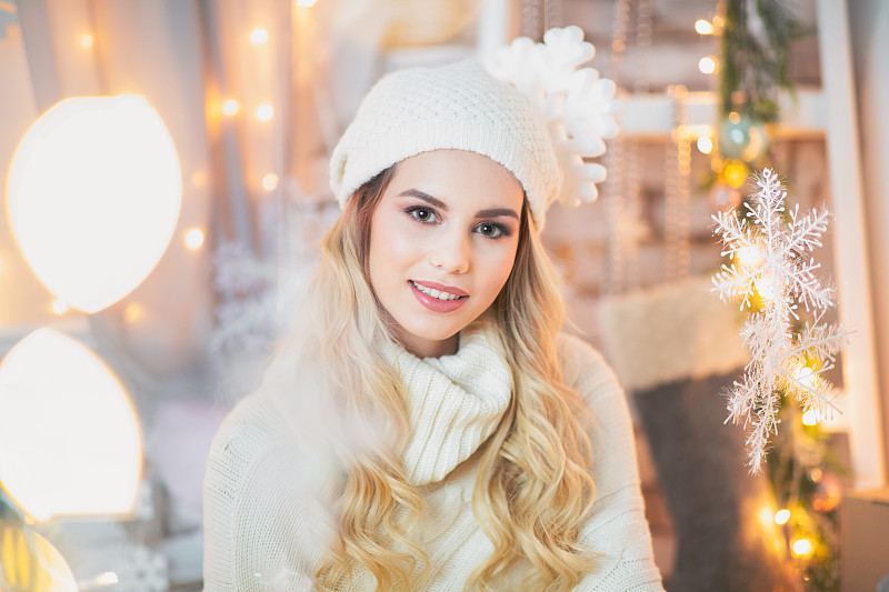 年轻女子坐在圣诞布景中，对着镜头微笑图片下载