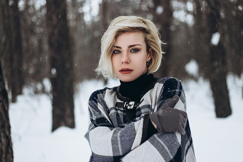 冰冻的年轻女子在白雪皑皑的森林。图片下载