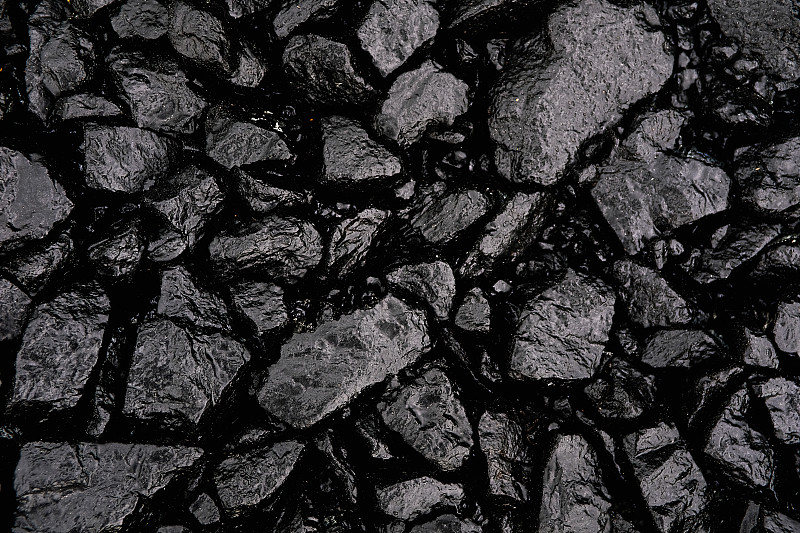 用于道路建设和重建的灰色或黑色碎石或碎石，浇上沥青。沥青的准备和铺设。纹理背景。建筑行业。图片下载