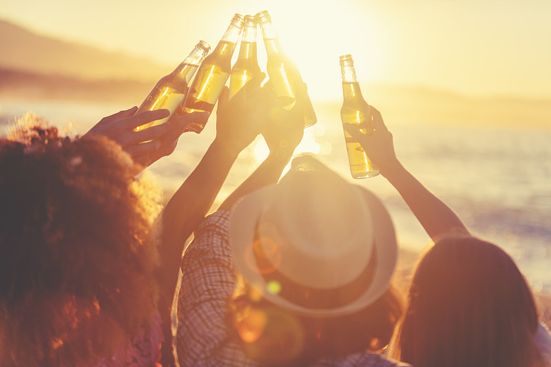 日落时分,一群年轻人在海滩上聚会。图片下载