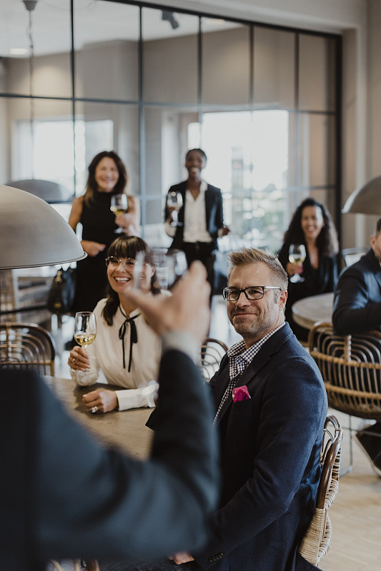 在办公室聚会上,微笑着敬酒杯的男女图片下载