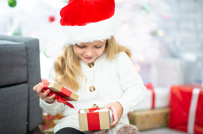 小女孩打开一个小小的圣诞礼物图片下载