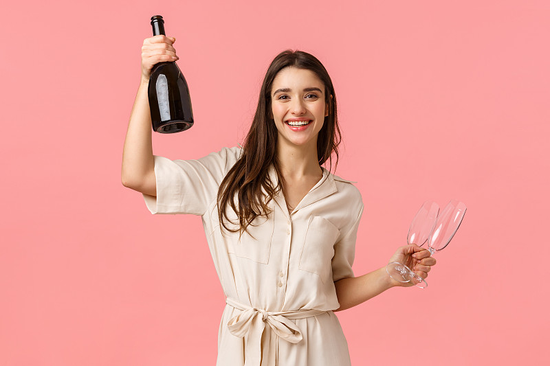 年轻女子的肖像微笑着拿着瓶子,而站在粉红色的背景图片下载